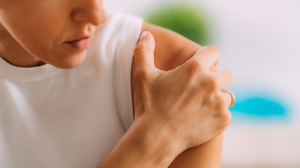 women clutching her shoulder in pain. Return to work after a shoulder injury. 