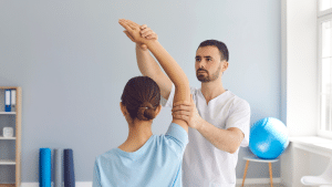 woman sitting down on a table with arm stretched upwards and man standing holding woman's arm up.